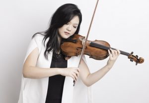 Emily Sun plays the violin against a white backdrop